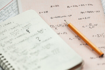 Math formulas are written in pencil on a piece of paper, math problems
