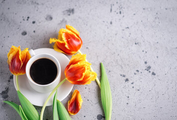 A cup of aromatic espresso coffee, a bouquet of red and yellow tulips, a postcard with copyspace for international women's Day
