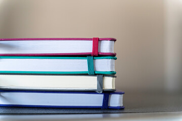 stack of multi colored notebooks and pencil on office table