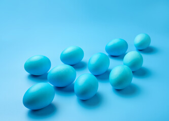 Several Easter eggs of blue color on a blue background with copy space.
