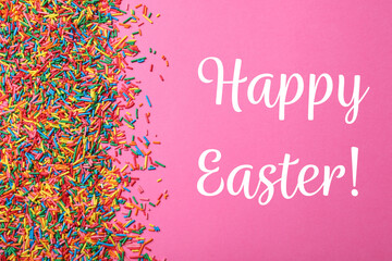 Text Happy Easter and colorful sprinkles on pink background, flat lay. Confectionery decor