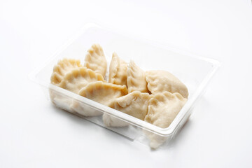 Pierogi, dumplings on a plastic, transparent food tray, isolated on white.