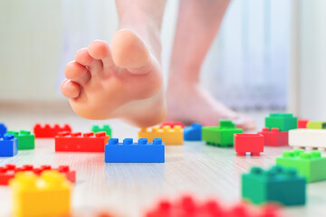 A second before.A person steps on a part of a children's construction kit with his foot.A man gets hurt