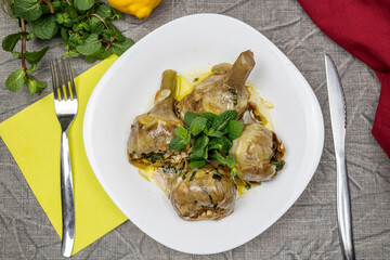 Roman-style artichokes with mint. Traditional Italian cuisine dish. Artichokes alla Romana. Flat lay.