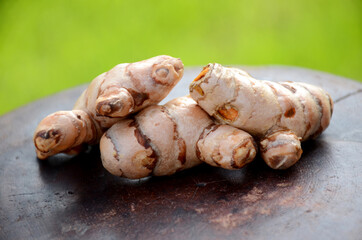 the brown orange ripe turmeric on the green brown wooden background.