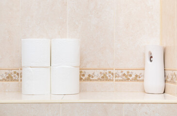 Rolls of white toilet paper and air freshener on the toilet shelf. Modern electric air freshener.