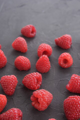 Pattern of raspberry on dark rock background. Flat lay summer berries - red raspberries. Creative minimalism. Frony view