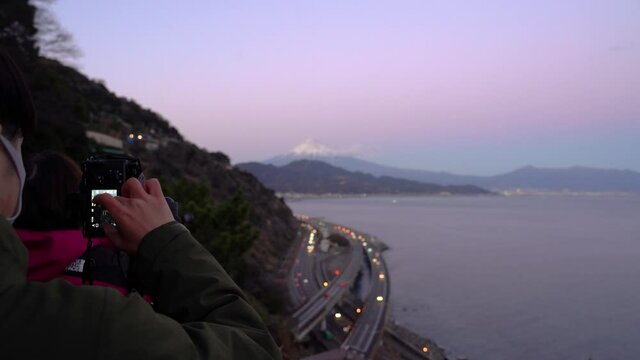 Photographer wearing facemask during Covid Pandemic taking pictures of landscape with Mount Fuji