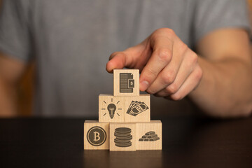 Business and finance concept. Hand holds wooden Wooden blocks with finance icons. securities, securities, money, idea, bitcoin, coins, gold on background human