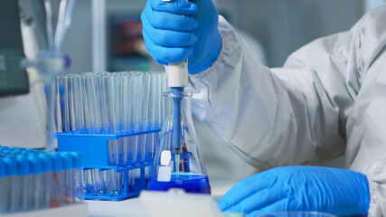 Close up of researcher testing liquid sample using micropipette for new treatment medical laboratory. Team of doctors examining virus evolution using high tech for vaccine development against covid19