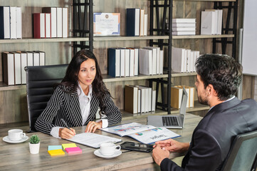 A woman boss businesswoman shaking hand with a businessman candidate at an office desk in an interview or meeting.