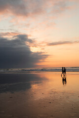 
Silhouettes of people walking at sunset on the beach of Oyambre, San Vicente de la Barquera, Cantabria, Spain