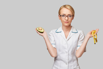 nutritionist doctor healthy lifestyle concept - holding organic avocado fruit and measure tape