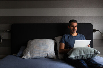 Fototapeta premium Man working in bed with a digital tablet