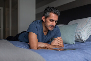 Man reading in bed with digital tablet