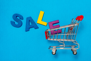 Empty shopping cart and inscription SALE on blue background
