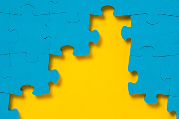 Unfinished blue jigsaw puzzle on yellow background with copy space