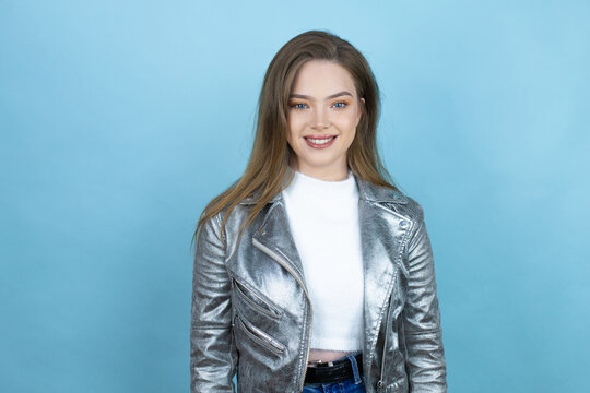 Pretty woman with long hair wearing a casual jacket over blue background with a happy face standing and smiling with a confident smile showing teeth