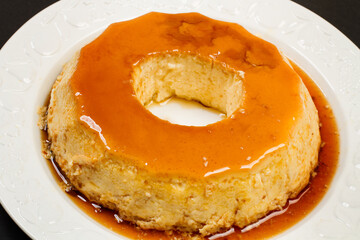 Flan casero sobre un plato blanco redondo. Vista superior y de cerca