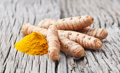 Turmeric root with curry powder on old wooden background