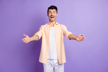 Photo of optimistic brunet guy hands want hug wear peach shirt pants isolated on lilac color...