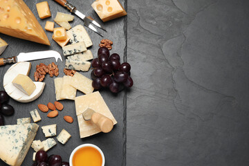 Fototapeta na wymiar Cheese platter with specialized knife and fork on black table, flat lay .Space for text