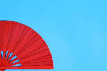 Red hand fan on light blue background, top view. Space for text