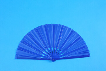Hand fan on light blue background, top view