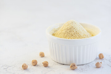 Fototapeta na wymiar Chickpea flour in a white bowl on a light background.