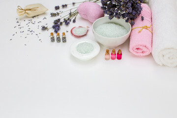 Spa cosmetics sea salt and towels,  aroma oils and dry lavender on a white background with a copy of the space