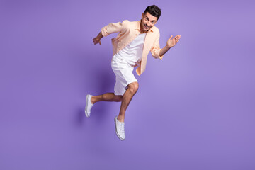 Full size profile photo of optimistic brunet guy jump run wear peach shirt shorts footwear isolated on lilac background