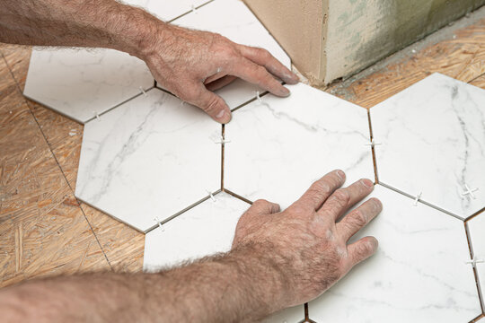 Renovation works - interior finishing worker (tiler) laying ceramic tiles on the floor