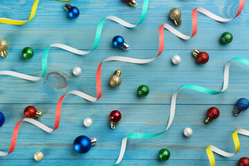 Colorful serpentine streamers and Christmas balls on blue background, flat lay