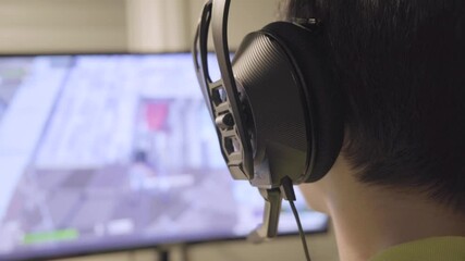 ESports Gamer boy playing fortnite. Professional teen in action with Fun Special Effects on His Personal Computer. Cyber Gaming Tournament Championship. Over the Shoulder Camera Shot Close up of