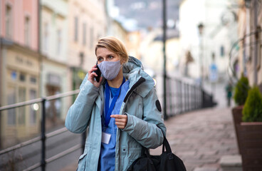 Fototapeta premium Woman healthcare worker outdoors on the way to work, coronavirus concept.