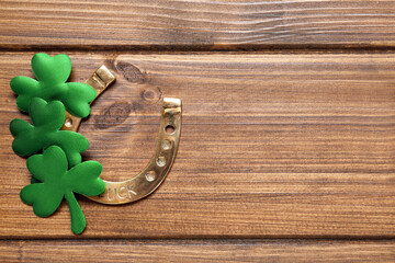 Clover leaves and horseshoe on wooden table, flat lay with space for text. St. Patrick's Day...
