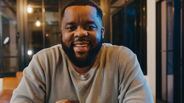 Middle-aged African American male feeling happy smile and look at camera using phone make video call in living room at home night. Social distancing, quarantine for coronavirus. Close up webcam view.