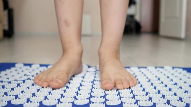 Unrecognizable teen boy stands up bare feet on the spiked mat.
