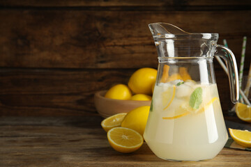 Cool freshly made lemonade in glass pitcher on wooden table. Space for text