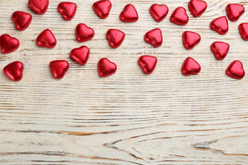 Heart shaped chocolate candies on white wooden table, flat lay with space for text. Valentines's day celebration