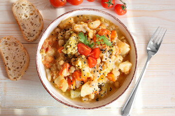 A plate of vegetable stew on a wooden background top view
