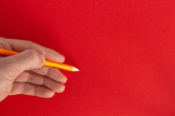 Hand holds a pencil on a colorful background