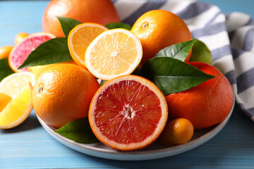 Different citrus fruits on light blue wooden table, closeup