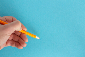 Hand holds a pencil on a colorful background