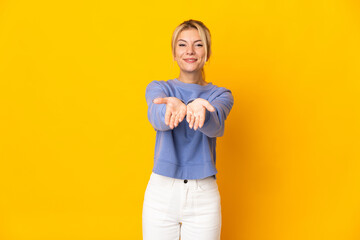 Young Russian woman isolated on yellow background holding copyspace imaginary on the palm to insert an ad