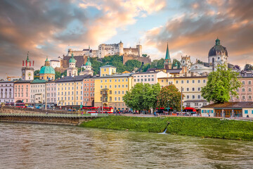 Naklejka premium View to Hohensalzburg Fortress and Staatsbruecke bridge across Salzach river on a spring evening with many people walking