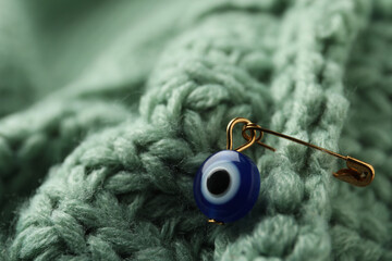 Evil eye safety pin on knitted clothing, closeup