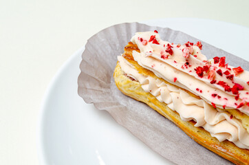 Eclair with cream and strawberries. On a white plate High quality photo