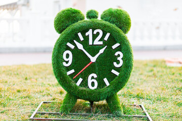 Landscape design. Green alarm clock made of artificial grass. The concept of time management