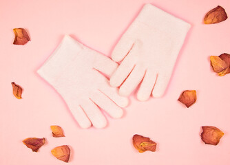 Spa gel moisturizing gloves and rose petal on pink background. Tenderness skin care concept.